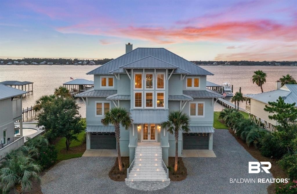 Deep Water Living on Bayou St. John – Ono Island!!  Need deep water for your large yacht? This custom waterfront home is located on the northwest side of Ono Island along the beautiful waters of Bayou St. John, offering approximately 11 feet of water depth and convenient access to Perdido Pass. The private dock features two boat slips—one accommodating a 65+ ft vessel and a second slip with a 16,000 lb lift for a large Center Console boat or Pontoon. The dock also includes storage and a fish cleaning station, making it ideal for boating and fishing. Inside, the gourmet kitchen with GE Monogram appliances overlooks the expansive great room and waterfront views, creating a perfect space for gathering and entertaining. Unique architectural elements include jellyfish chandeliers highlighting the grand staircase. The home offers 7 bedrooms and 5½ baths, including two primary en-suite bedrooms on the main level, both opening directly to outdoor living spaces. Additional features include a built-in elevator, natural gas fireplace, and main-level laundry.  Downstairs you have a full Captain's Quarters complete with Sleeping for 6, a Full Kitchen, Laundry Room, Living area and meeting room for planning out your fishing strategy before setting out on our beautiful Gulf Waters. Outdoor living is designed for relaxation with a saltwater pool, hot tub with waterfall features, and spacious entertaining areas furnished with Polywood outdoor furniture, all overlooking the tranquil waters of Bayou St. John. Built with quality and durability in mind, the home features poured-in-place concrete construction, impact windows, and a standing seam metal roof. The property offers approximately 6,013 square feet of living space and 102± feet of waterfront. A rare opportunity for deep water living in Orange Beach with exceptional boating accommodations. Buyer to verify all information during due diligence.