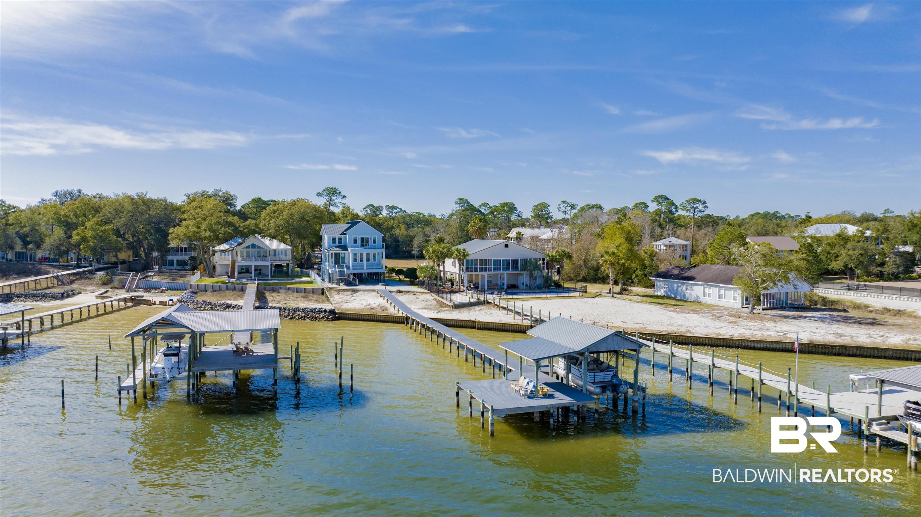 29919 Bayland Dr — Exceptional bayfront living on Bear Point with rare, unobstructed north and east views delivering breathtaking sunrises and expansive water vistas from multiple rooms. Situated on a quiet dead-end street in a golf cart-friendly community, you’ll enjoy the convenience of accessing local restaurants and live music by golf cart.Positioned on a high lot, this property offers valuable peace of mind — no flood insurance required — along with a double seawall for enhanced waterfront protection.Completely renovated in 2022, the home features updated electrical and plumbing, beautifully updated kitchen and baths, and durable luxury vinyl plank flooring throughout. The exterior showcases concrete board siding and a standing seam metal roof for long-lasting protection and coastal curb appeal.This spacious layout includes 4 bedrooms, 3 full baths, and 2 half baths, with two primary suites — one on the second floor and another on the third — ideal for guests or multi-generational living. A convenient ground-level half bath is paired with multiple storage closets for added functionality.Outdoor living is designed for enjoyment and low maintenance. The lot is fully covered in crushed granite with paver accents perfect for entertaining. Balconies feature composite decking with stainless steel cable railings to maximize both durability and views.Boaters will appreciate the dock with composite storm-resistant decking and a boathouse equipped with a 10,000 lb lift and covered deck.A rare opportunity to own a fully renovated, move-in-ready bayfront retreat in one of the area’s most desirable waterfront communities. Buyer to verify all information during due diligence.
