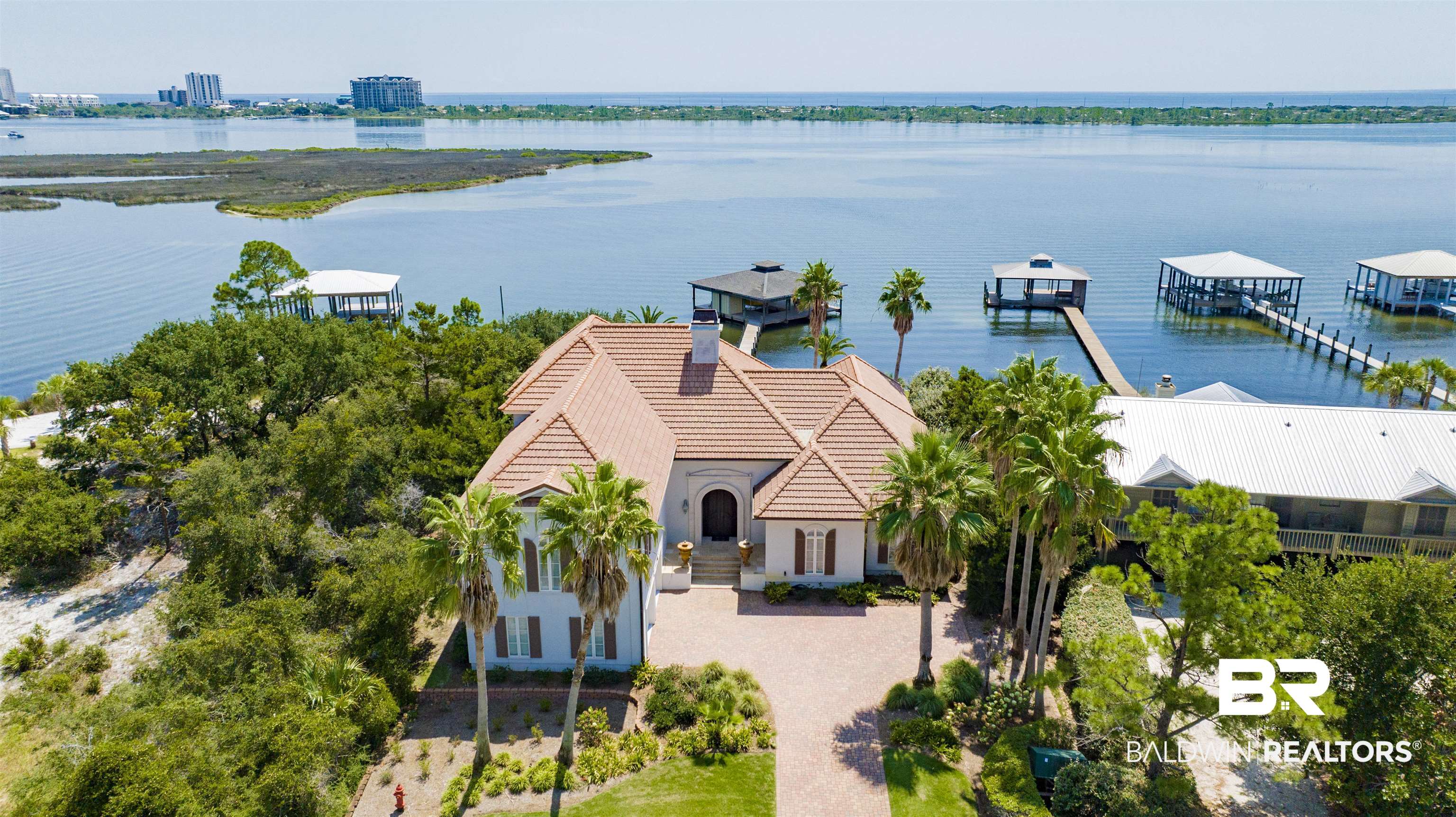 This is one of those rare Ono Island lots that makes you stop and stare.Just under half an acre with more than 80 feet of prime frontage on the Old River, giving you wide-open water views that change with the light all day long. The lot feels generous and private, and the dock is already in place and ready for you: 39 x 39 feet with a 10 x 29 slip and a 2021 boat lift. You can pull in, tie up, and be inside in minutes — it’s the kind of setup any boat enthusiast would love to own.The house (Mediterranean style, 4,943 square feet, four bedrooms, five baths) was built to high standards that were ahead of their time and has withstood the test of many storms. The entire interior and exterior have been freshly painted, so everything feels bright, crisp, and clean. It comes fully furnished, and honestly, you have to SEE THIS IN PERSON, it's beautiful — the kind of home where you walk in, exhale, and immediately feel like you could live here forever.Main level opens to those river views with a bright living and dining area, a kitchen you’ll actually enjoy using, the primary suite, a flexible recreation room, and a real home gym. Upstairs you get three more bedrooms (each with its own bath) and a large cozy sitting area with flexible uses.You could move in tomorrow and start enjoying the views (and the dock), or take your time and put your own stamp on it later. The solid construction, the lot size, the waterfront setting, and that dock are already locked in.Ono Island perks are all included — gated entry, community pool, tennis, boat ramp, clubhouse — but this address is really about waking up to that river every morning with your boat right outside.  If you’ve been searching for a big, beautiful waterfront lot on the Old River with a very well-built home that’s ready to move in — plus a dock that’s actually usable the day you close — this one checks every box.  Buyer to verify all information during due diligence.