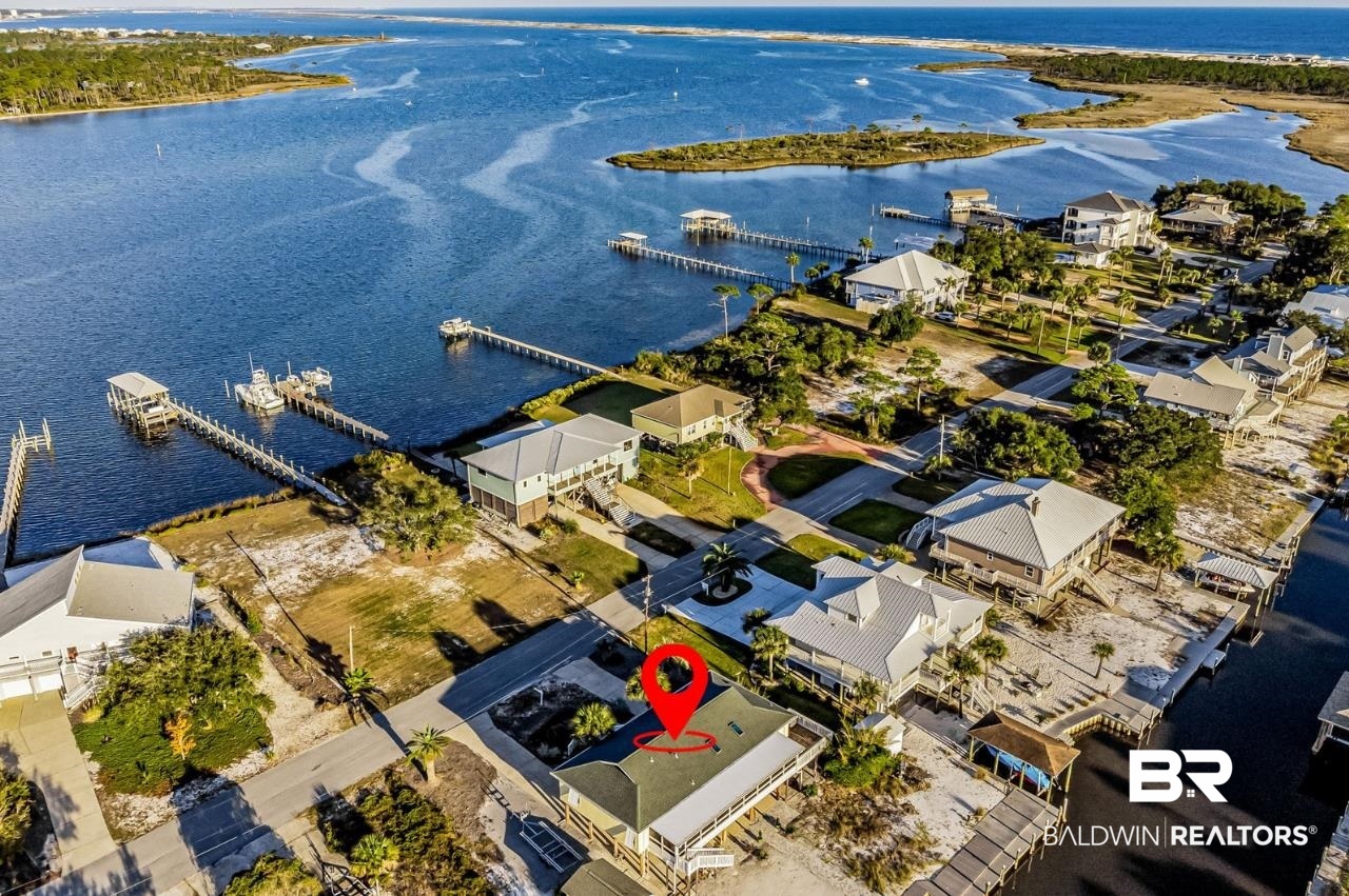 PRIME WATERFRONT LOCATION WITH EASY ACCESS TO PERDIDO KEY’S BEAUTIFUL AREA WATERWAYS!  This well-maintained home is perfect for the boating and watersport enthusiast or just someone looking to enjoy island life. Within easy walking distance or golf cart ride to the Oyster Bar restaurant and the new Perdido Key multi-use path! This canal-front home is situated on 100 feet of deep-water and has an 8,000 lb. boat lift, newer vinyl seawall and staircase leading into the water for convenient boarding of your kayak, paddle board or jet ski. This spacious 3-bedroom residence has plenty of room for the family and comes with AN ADDITIONAL 500 ft.² OF GUEST QUARTERS ON THE LOWER LEVEL (NOT INCLUDED IN SQUARE FOOTAGE). Inside the home, you will find a beautifully remodeled kitchen with granite countertops, eat-in island, stainless steel appliances, and modern cabinetry. An extra-large laundry/utility room has convenient access to the exterior elevator, (Harmar vertical lift). Come home to a living area that feels bright, spacious and cozy with fireplace, vaulted ceilings, skylights and plenty of windows. The outdoor living space has gorgeous Intracoastal Waterway views from the front porch and includes a 500 square-foot covered, screened back porch which is perfect for entertaining or just relaxing (hot tub included). The low-maintenance, natural landscape is ideal for second homeowners or those who like to travel. Other stand out features of this home include Bahama shutters, composite decking, 2019 HVAC, 2020 ROOF, bonus enclosed storage at garage level, and freestanding yard building/workshop with power and workbench. Plus plenty of covered parking space for vehicles, boat trailers and your RV! Welcome Home to Perdido Key’s laid-back Island Life!
