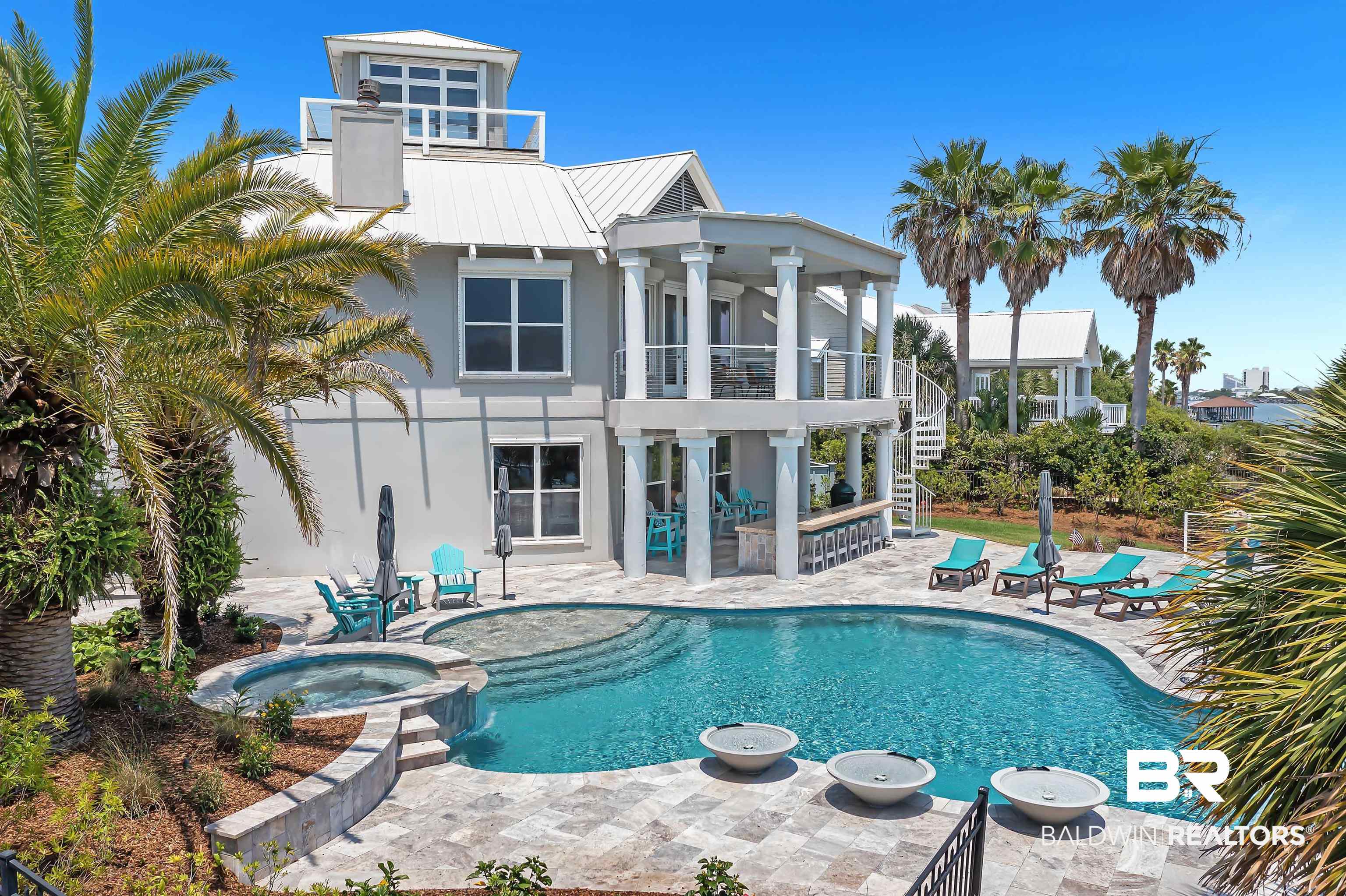 Welcome to private Ono Island! This beautiful waterfront home is located on Old River and has an incredible outdoor living space that will make you feel like you're at a resort! A lovely outdoor kitchen with a sink and a Green Egg and plenty of prep/counter space, a simply beautiful infinity edge pool with an integrated hot tub, travertine tile on the entire large pool deck, an outdoor shower, new pier leading to a boathouse with two slips and quick access to the Gulf...what more could you ask for?   On the ground floor you will find a foyer, two guest bedrooms with ensuite baths, and a bar/lounge space that opens up to the outdoor kitchen and stunning pool area. There is a door that connects to the garage as well as storage on this level.  On the 2nd floor you will find a kitchen/dining/living space with amazing views. The living room has a fireplace with great storage on either side. There is a guest room on this level that has a Jack-and-Jill bath that is shared with the living room. This is also where you will find the large primary suite. It includes the bedroom, bathroom with a jacuzzi tub, separate shower, double vanities and two walk-in closets. When you pass through the bathroom you will find a space that would make a great office or sitting room with another closet. Storage is no problem in this beautiful home!  On the third floor you will find a cupola with simply incredible views that have to be seen to be believed. There is an elevator as well as fantastic storage throughout.  This home is not to be missed! Schedule your appointment today!
