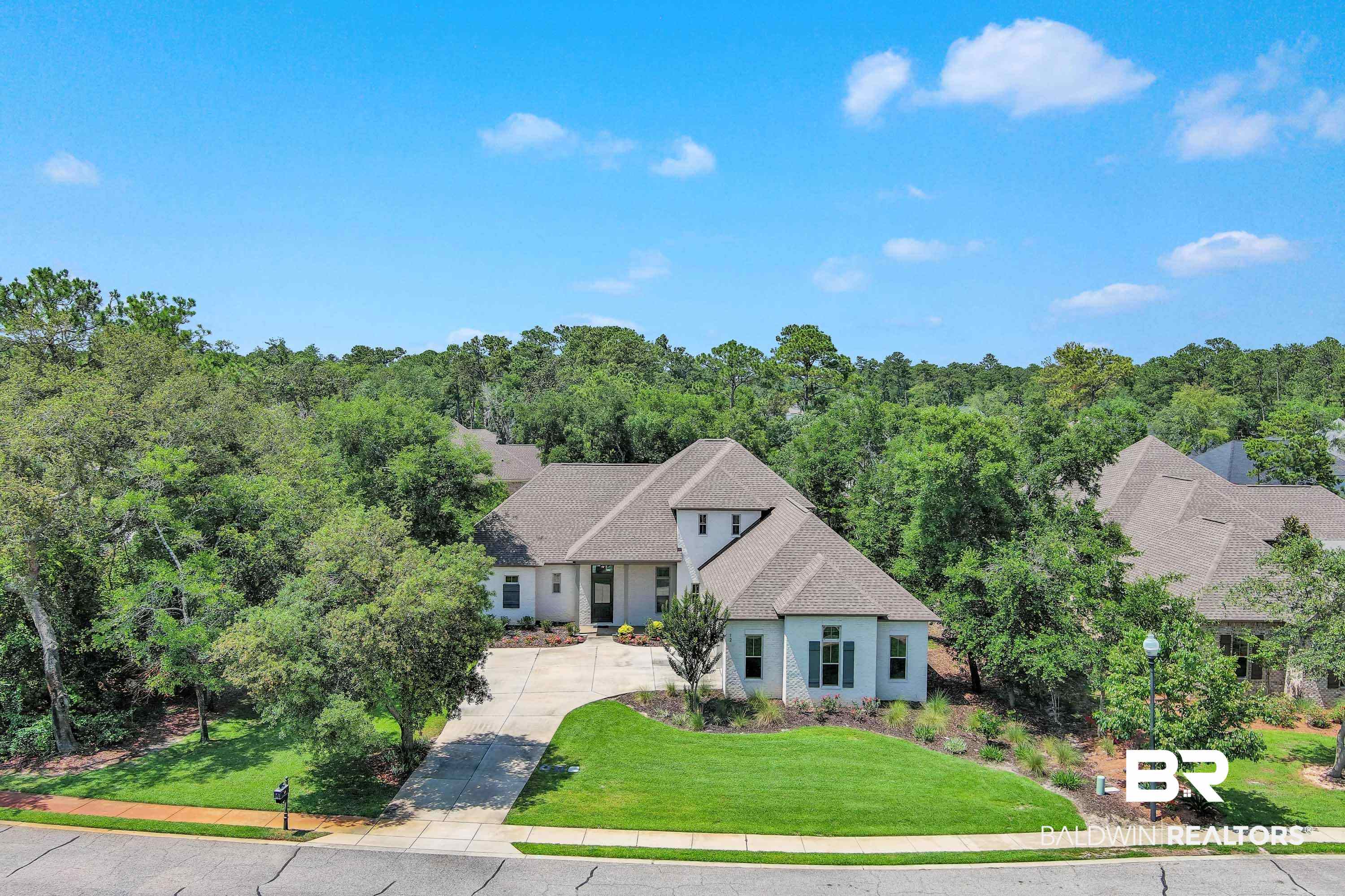 Nestled in the idyllic setting of one of Gulf Shores’ most sought-after communities, this Gold Fortified 3,308 sq. ft. custom brick home occupies a spacious corner lot in The Peninsula across from the Cypress Course holes 5 and 6. With a large wooded common area directly to its west and north, this home’s lot offers enhanced privacy and a green space that wraps the residence in natural seclusion. Built in 2017, this one-owner home has been designed as a contemporary and restful coastal retreat. In 2020, a new heated saltwater pool with Baja ledge and fountain, Coolcrete pool deck, fencing, landscaping, and screened enclosure were installed. This outdoor area also offers a gas fireplace and spot for a flatscreen TV. Stepping inside the front entry, the beauty of the landscaped grounds flows into a welcoming foyer with wood staircase, to a sunken dining room with exposed brick feature wall, into an inviting living area and gourmet kitchen with an oversized granite island, pendant and recessed lighting, soft close cabinetry, stainless appliances, and coffee bar. The first floor has 10’ ceilings, 8’ doors, hand-scraped wood and 12x24 tile floors, and elegant trim. The main floor primary suite features a stunning free-standing tub, glass/tile shower, dual vanities, and walk-in closet. The guest bedrooms upstairs have their own full baths and share a separate lounge/office area. Additional rooms include a 1/2 bath, 2 pantries, extra-large utility room, office, and oversized 900 sq. ft. garage that’s big enough for the addition of a golf cart door, if desired! Peninsula owners have access to impressive amenities - indoor/outdoor pools, fitness, yoga, massage, tennis, pro shop, trails, bar & grill, and a private pier on the bay! An agreement with The Beach Club resort gives owners easy Gulf access and use of their award-winning beachfront amenities! A 1-Year Home Warranty is included, and new owners of this home can get 75% off the 27-hole golf membership initiation fee!