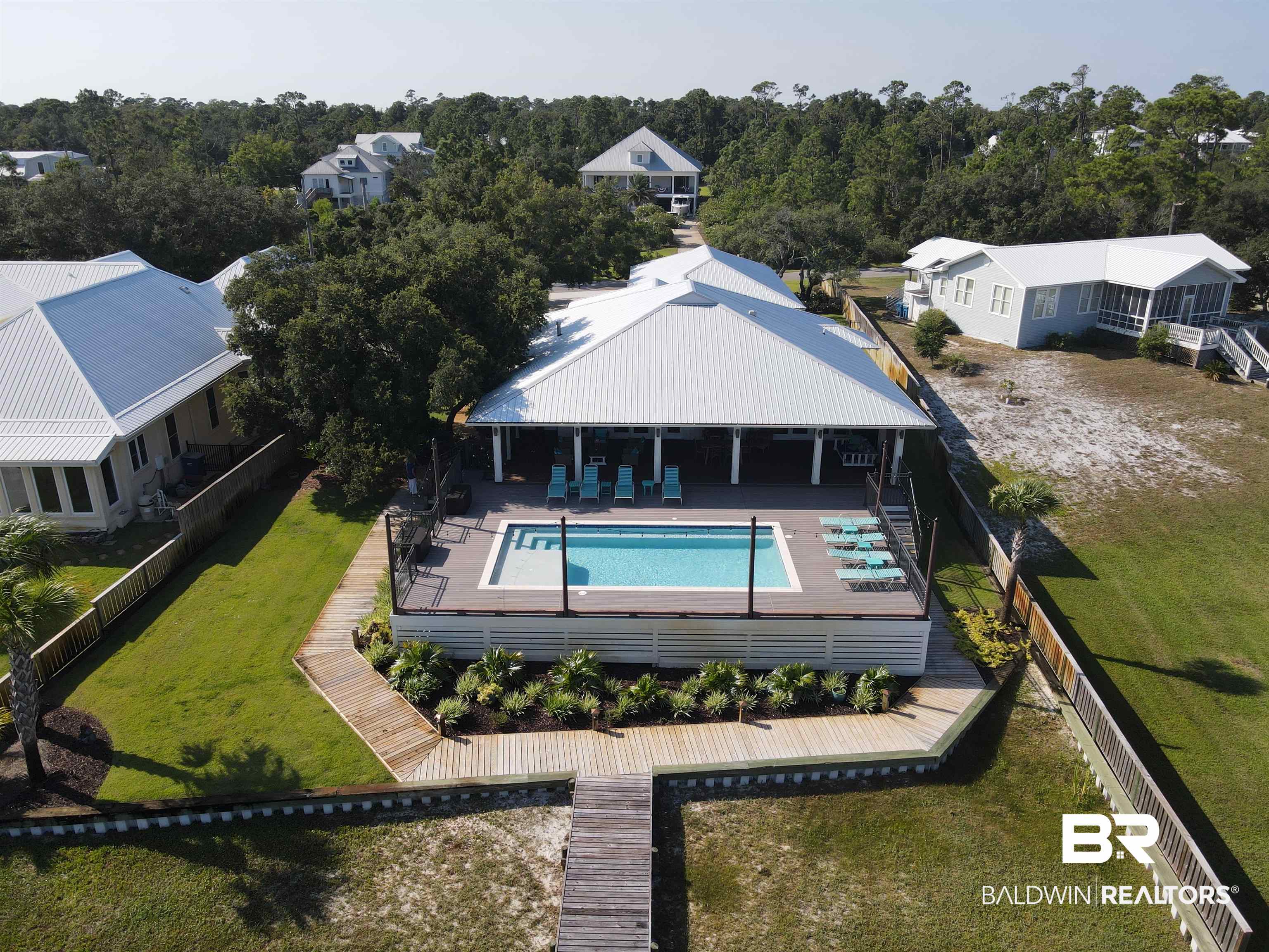 Price reduction so that you can start living in this waterfront community embracing a lifestyle of both elegance and relaxation. Whether it's a morning coffee with the sunrise over the water, hosting gatherings on your waterfront patio, or setting sail on your boat whenever the mood strikes, this home offers a seamless blend of luxury and leisure. Step inside this exceptional home that combines versatile living spaces with luxurious details. From the whitewashed pine walls to the stained tongue and groove stained pine ceiling, each element has been chosen to create an atmosphere of comfort and rustic elegance. The open floor plan of kitchen, dining and living with custom cabinetry, quartz counters, oak hardwood floors and a cozy fireplace add to the charm. Boasting 3 well appointed bedrooms and a versatile office that is currently used as a 4th bedroom, this residence caters to a variety of lifestyle needs. The spacious primary bedroom offers views across the pool to the sparkling Bayou. The bathroom is a sanctuary of relaxation and indulgence. Featuring a large walk-in shower, where you can unwind. The freestanding tub invites you to soak away the stresses of the day while enjoying the serene water views. The double vanity adorned with quartz countertops exudes contemporary sophistication and offers ample space for your daily routines.  Step into an outdoor paradise that complements the interior of this home, extending the living space seamlessly. The highlight of the outdoor area is the expansive covered porch that spans the entire length of the house, offering unobstructed views in both east and west directions. A pristine gunite pool, full outdoor bathroom and electric hurricane screens that offer reliable protection during challenging weather. The pier, boathouse and lift extend the outdoor experience and give instant access to the Gulf of Mexico.    Furniture negotiable. No personal items, Art work, decorative furnishings tools etc convey.