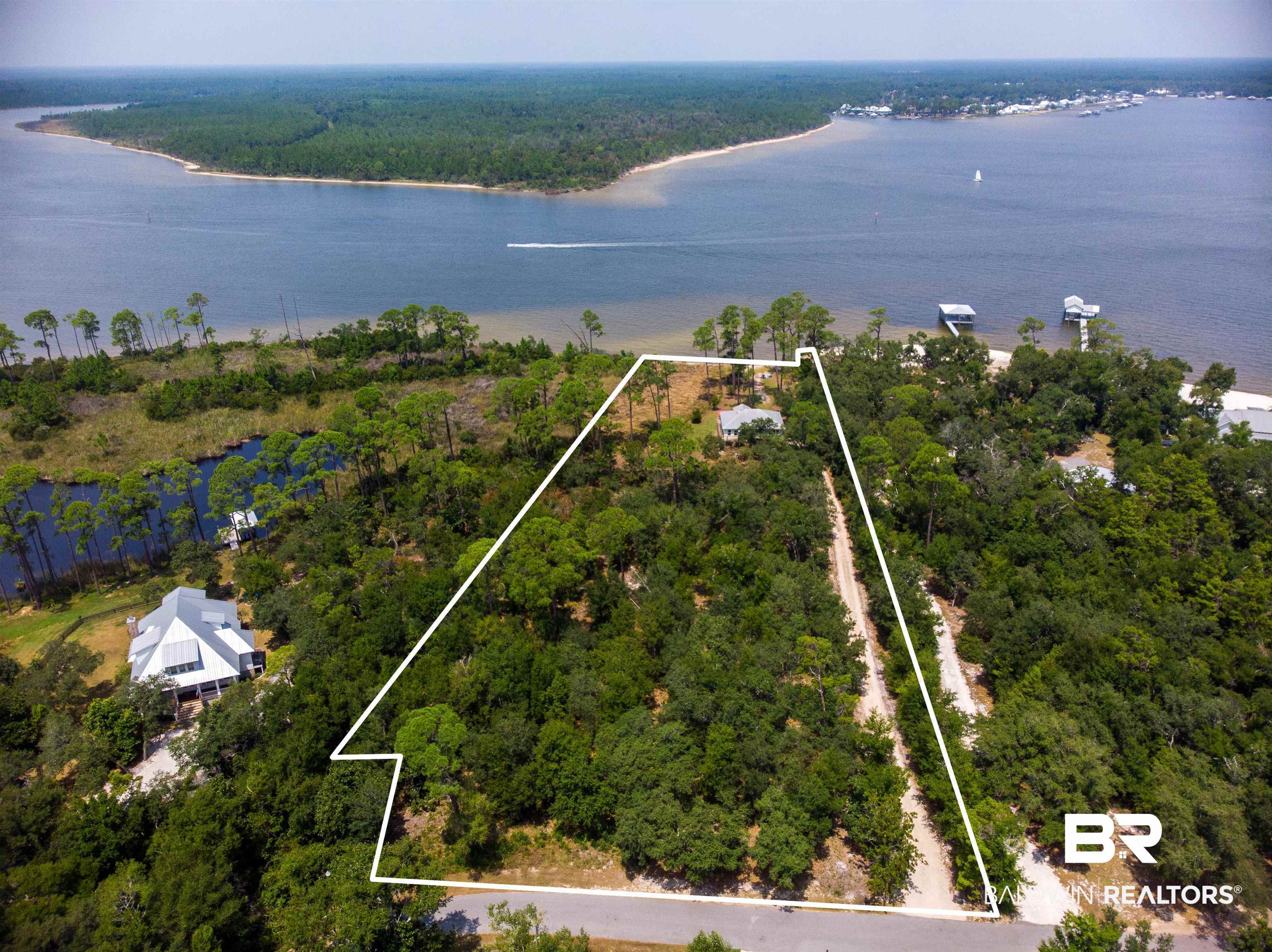Rare waterfront acreage with a lovely partially furnished beach cottage.  3.2 acres with 151 of waterfront on Bay La Launch.  Located on Sampson Ave, this property is a virtual nature preserve with eagles, deer, and let's not forget daily dolphin sightings.  You can build a single home or a compound !  Custom house plans for a 3200 sq ft house included.  This property has no HOA.  PERMIT FOR SHORELINE MPROVEMENT AND BOAT DOCK/PIER AND DREDGING HAS BEEN APPROVED AND PERMIT IS IN HAND.  This property is, dare we say, Magical ! Buyer to verify all information during due diligence.