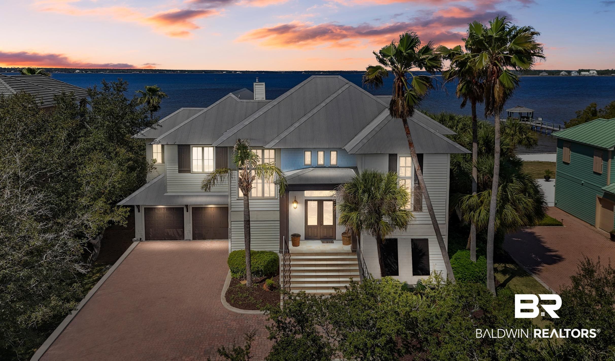 This Gorgeous Waterfront Home is the Epitome of Coastal Elegance!  Located in one of the most desirable areas within Ono Island and on Ono Harbor, these homes rarely come on the market! This beauty boasts direct water access from the front and back of this home!  Every room of this Gorgeous home has fabulous water views from the expansive large windows.  Enjoy and Entertain with your own private white sandy beach, beautiful pool, multiple covered decks and patios, stainless outdoor kitchen, and a private pier with two boat slips that includes a lift.Inside this home you will find high ceilings, Travertine Flooring, Stained Doors, Chef's kitchen with high end appliances including a Wolf gas range, quartz countertops, massive bar area with beverage cooler and Ice machine, dining and large living area with fireplace and built ins.  The Primary Suite is massive with high ceilings, huge windows overlooking Bay St. John, Balcony off of the bedroom, a Beautiful Large Bath with Separate Steam Shower, Tub and Double Vanities.  You will love the Cozy and Warm Den on the Lower Level with a bar with beverage cooler and Ice machine.  This home also features Laundry rooms on both floors and Central Vacuum.  This meticulous and well maintained home has beautiful landscaping with a large double garage and lots of storage.  New A/C just installed and New Mist-A-Way System for the landscaping.  This home has been updated with new paint, coffered ceilings, and includes an ELEVATOR, Heated and Cooled Garage, Large Work area off of the garage and much more! Ono Clubhouse with Tennis, pool and exercise just a short walk.  Don't wait on this one!!