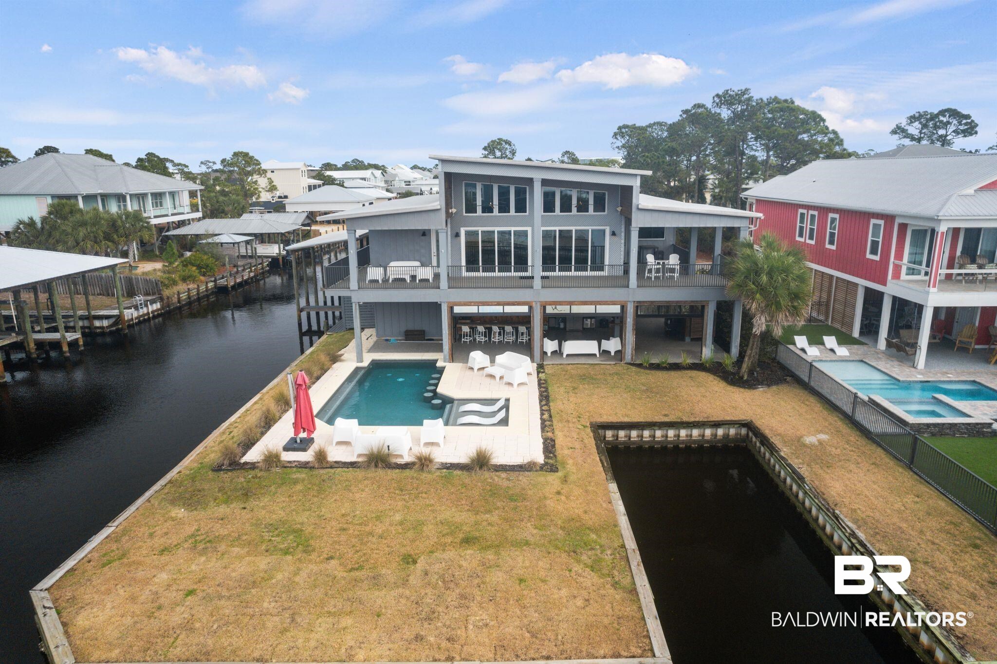 Experience waterfront living at its finest! This stunning one of a kind home is perfectly nestled on a corner lot at the end of Cotton Way. Featuring three bedrooms with ensuites and a one bedroom/one bathroom separate downstairs apartment. This luxurious Gold Fortified custom-built home offers a beautiful blend of traditional elegance and serene waterfront living. The heart of this home is the spacious open concept living area featuring expansive windows and sliding glass doors that showcase the stunning water views. The modern kitchen is equipped with premium appliances, two large double islands with built-in cabinets and ample space for cooking and entertaining. Large walk-in pantry offers a second refrigerator for overflow. The exterior features an amazing outdoor living space with a heated and cooled saltwater pool, covered boat dock with lift, heated and cooled storage room, large bar area that can be partial enclosed with 4 glass rollup doors and so much more! The property offers a rare combination of luxury, functionality, and direct access to coastal recreation. Buyer to verify all information during due diligence.
