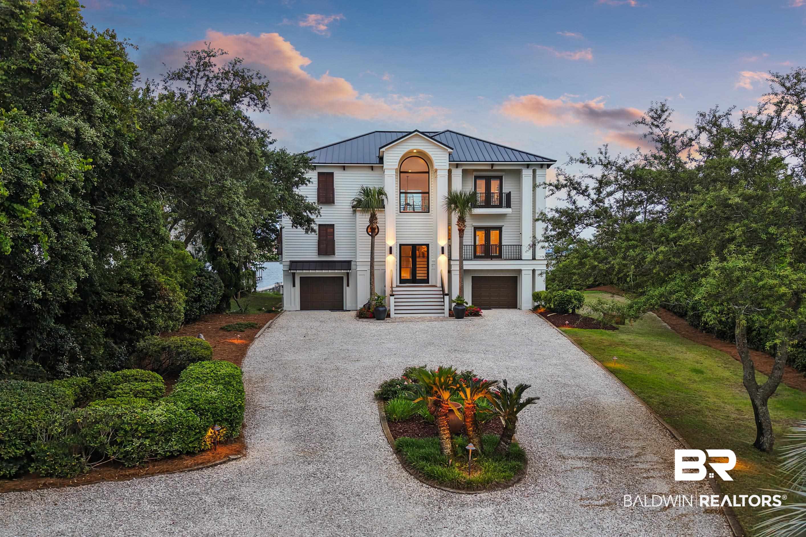 Experience unparalleled luxury with this stunning 4-bedroom, 4.5-bath home perfectly positioned on a private and beautifully landscaped 1.09-acre lot on Ono Island in Orange Beach, Alabama. The home's exterior features new artisan hardboard siding, a fortified standing seam metal roof, TimberTech composite decking and powder-coated aluminum handrails, ensuring durability and modern elegance. The grand 8-ft hurricane impact front doors and new electric hurricane shutters on all floors add security and peace of mind. Step inside to find a beautifully upgraded kitchen, complete with quartz countertops, high-end cabinetry, a professional-grade 48-inch Wolf gas range, and stainless steel appliances. The open-concept living area boasts high ceilings and large windows that flood the space with natural light and offer breathtaking views of Old River. The main-floor master suite offers a private retreat, ideally located for convenience and solitude. Upstairs, two generously sized guest bedrooms with en-suite bathrooms, share a spacious sitting/TV room, perfect for relaxed evenings or hosting friends and family. The versatile 4th bedroom on the lower level can also serve as an office or leisure room, adding flexibility to the home's design. Outdoor enthusiasts will delight in the private boathouse, complete with 2 boat lifts, a 8,000-lb lift currently being used as a kayak/paddle-board launch and a 12,000-lb lift, fish cleaning station, sun deck and an entertainment bar area. Relax and entertain on the private beach, surrounded by landscape lighting that enhances the property's ambiance. Additional highlights include a new 80-gallon commercial-grade water heater, new 400-amp electrical service to the house, new 400-amp electric transfer switch ready for a whole-house generator, and ample parking for guests. This home is a rare blend of modern upgrades, classic charm, and waterfront luxury. Don't miss the chance to own this fully furnished, exceptional property on Ono Island!