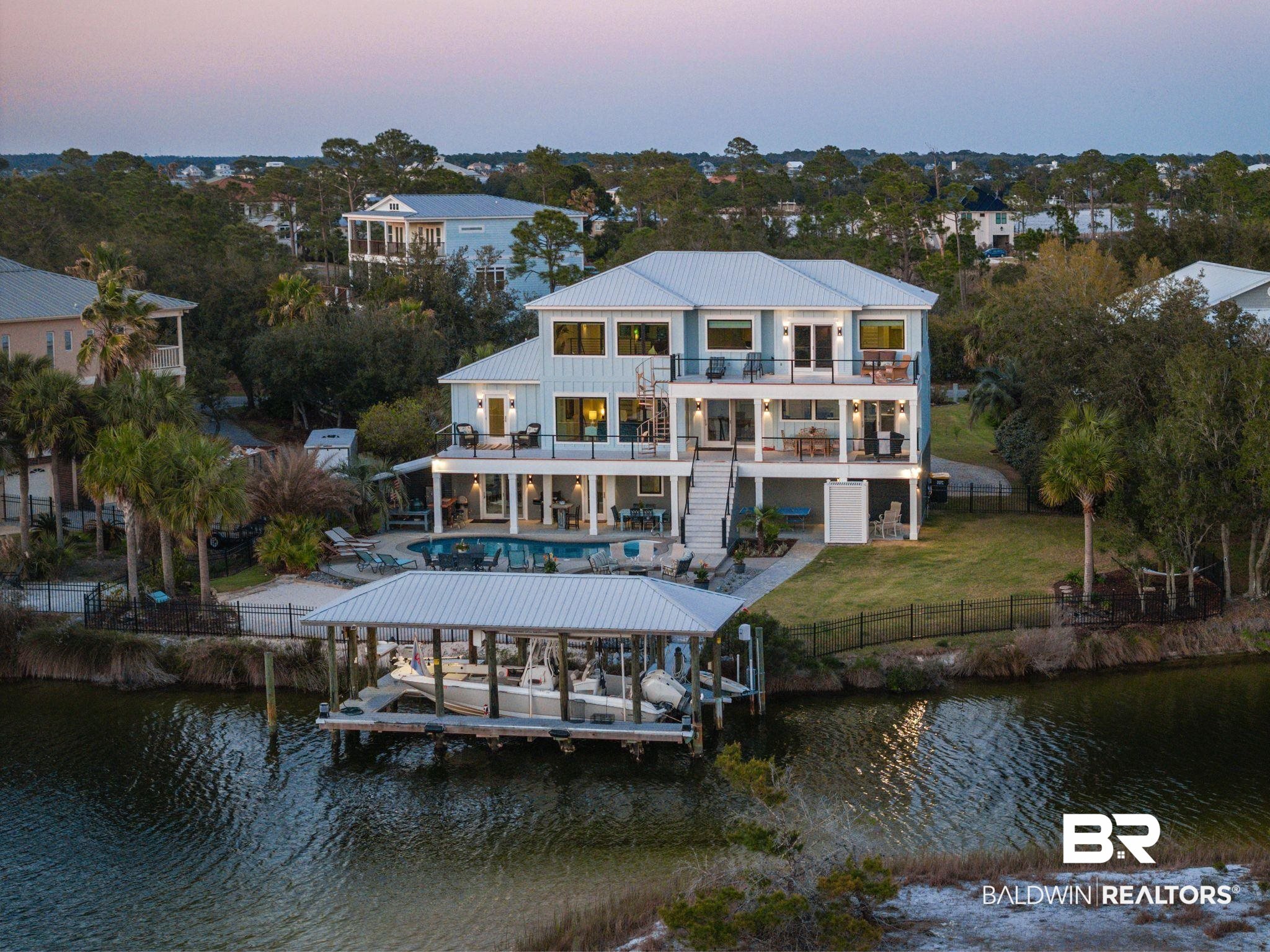 This is your dream waterfront retreat—a completely TRANSFORMED, custom-upgraded home offering the perfect blend of modern luxury and laid-back coastal living. This meticulously renovated 4-bedroom, 4.5-bath home features two private offices, a spacious den with a full bar including double beer tap —ideal for entertaining or relaxing in style, and an additional 120 sq ft heated and cooled rod and tackle room. The kitchen is a Culinary Haven that rivals Michelin restaurants, complete with Cafe Appliances, a food warming drawer and stunning views. Soak in sweeping water views from nearly every room, with walls of windows that flood the home with natural light. Step outside to your own backyard paradise featuring a resort-style pool, two balconies, and a covered boat dock with lift—all perfectly positioned for taking in unforgettable sunsets and waterfront breezes.The oversized primary suite offers panoramic water views, spa-like ensuite bath, and access to the upper balcony. Additional features include a whole-house gas generator, fully fenced yard, well-fed irrigation system, and countless upgrades both inside and out, new AC on 2nd and lower level (2025). (FULL LIST OF RENOVATIONS IN DOCS) Buyer to verify all information during due diligence.