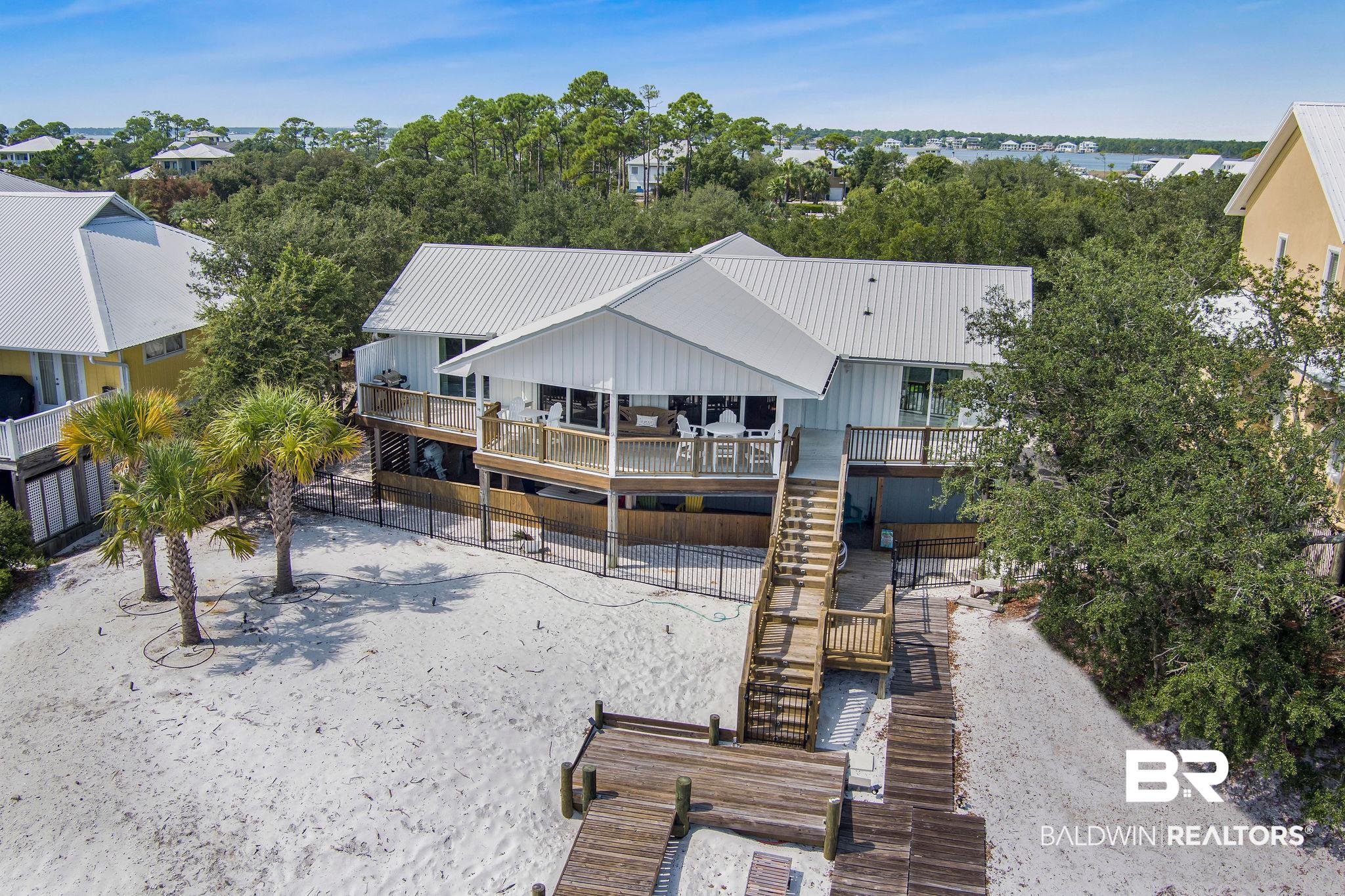 NO FLOOD INSURANCE REQUIRED! Boater’s Dream on the Bay !Welcome to your waterfront paradise! This stunning property boasts private, sandy white beaches—safe and shallow for kids to play, yet with a 5–6 ft deep draw for larger boats. Enjoy one of the best spots around for kayaking and paddle-boarding, with effortless beach launch access right from your backyard. The impressive boat house is a boater’s dream, featuring three lifts (12,000 lb, 10,000 lb, and a PWC lift), a dockside fish cleaning station, storage closet, three water hose stations, and ample lighting—all wired for TV, so you can relax or entertain dockside in style. Frequent visits from dolphins, manatees, fish, and blue crabs make every day feel like your own private nature show.Inside, the renovated home offers 3 bedrooms and 2 bathrooms upstairs, plus 2 additional rooms and a full bath downstairs—for guests or multi-generational living. The primary bedroom and second bedroom both feature sliding doors that open to a waterfront balcony, providing peaceful views and direct access to the coastal breeze. The living area also offers a beautiful view of Ole River, creating a light-filled, relaxing space you’ll never want to leave.Located on one of the highest elevations on the island, this property does not require flood insurance, offering peace of mind alongside its incredible views and amenities.Recent upgrades include a Bronze Fortified roof (post-Hurricane Sally), a new upstairs AC unit, and new mini-splits downstairs. The chef’s kitchen is equipped with KitchenAid appliances, an under-counter ice maker, and two refrigerated drawers—ideal for entertaining or everyday luxury.The fenced yard offers both privacy and security, completing this incredible blend of comfort, luxury, and coastal living.Call your favorite agent and schedule a private tour today! Buyer to verify all information during due diligence.