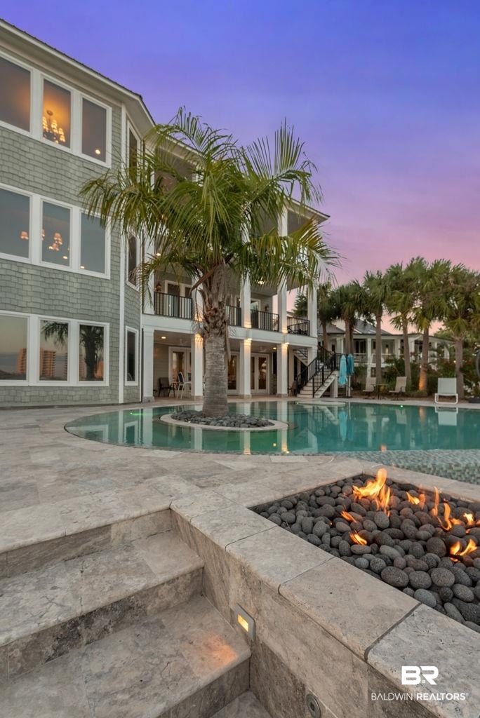 Situated in one of Ono Island’s most coveted waterfront locations, this exceptional luxury estate offers a rare opportunity directly across from the world-famous Flora-Bama Yacht Club and perfectly positioned at the no wake zone—allowing effortless access to Perdido Pass or a quick run to the Intracoastal Waterway. Elevated 13’ above sea level, this extraordinary property was designed for luxury coastal living with no detail overlooked. The home features a 47KW whole-house generator, whole-home audio/intercom system with Pandora, SiriusXM and Apple integration, wall-mounted TVs throughout, security cameras with remote access, commercial-grade 3-floor elevator, and extensive smart-home automation including WiFi-controlled blackout drapes and blinds. Designed for entertaining, the outdoor living spaces are unmatched with four finished porches featuring speakers, fans and lighting, travertine lower porches, and a spectacular automated infinity-edge saltwater pool with mirror-edge detailing, palm tree island, three propane fire pits, and expansive full travertine deck. The private beach area was enhanced with over 1,000 yards of dredged sand and lush tropical landscaping. The boathouse is equally impressive with FlowThru composite decking, widened boardwalk, 23’ boat lift, double jet ski lift, swim/sun deck, and electric service, creating the ultimate waterfront lifestyle. Inside, the home offers six bedrooms each with private baths plus two additional half baths. The custom wine room showcases wine barrel wall treatments, custom chandelier, and locally sourced barn door. The chef’s kitchen includes double JennAir double ovens, warming drawer, two dishwashers, and ice machine, while the lower-level kitchen makes the perfect guest or mother-in-law suite. This is coastal luxury living at its finest Buyer to verify all information during due diligence.